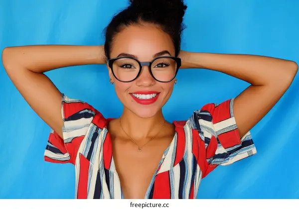 Happy Woman Wearing Stylish Glasses and a Striped Shirt against a Blue Background