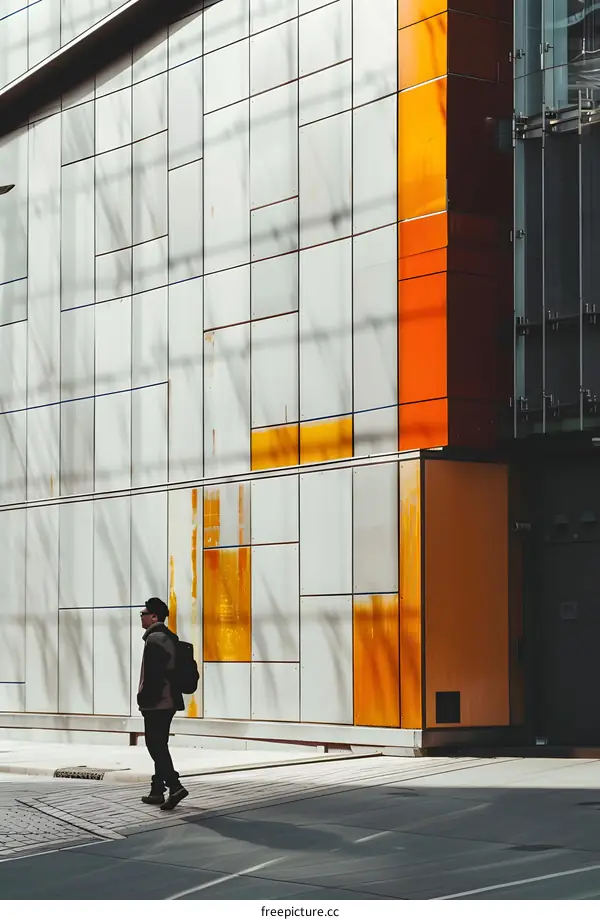 Man Walking Past Modern Building With Orange Panels