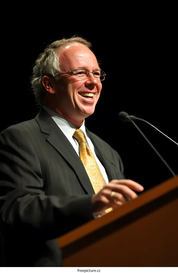 Smiling Man Speaking at a Podium with a Microphone