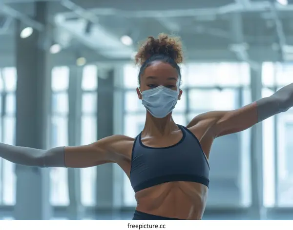 Black female dancer wearing a mask in a large empty room
