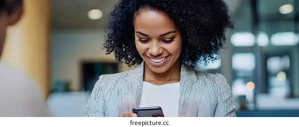 Smiling Black Woman Using Smartphone In Office