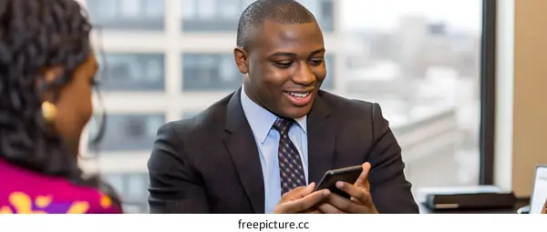 African American Man Smiling While Using Phone During Business Meeting