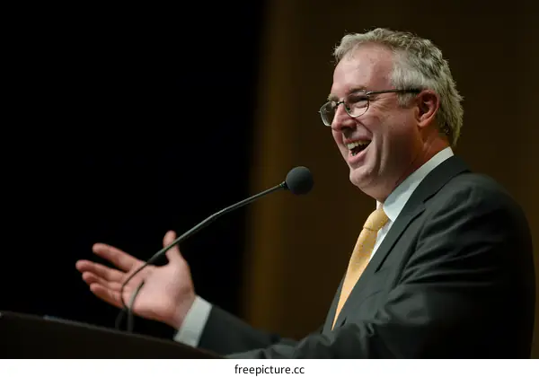 Caucasian Man Speaking at a Microphone in a Suit