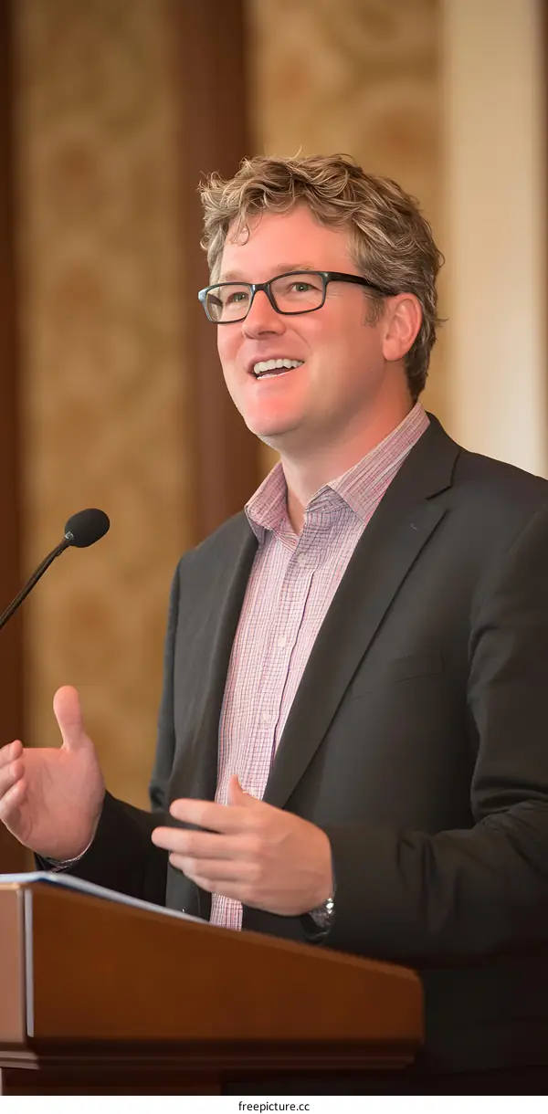 Man in Suit Speaking at Podium with Microphone
