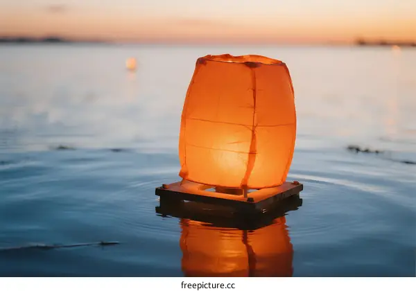 Floating Orange Lantern on Calm Water Surface at Sunset