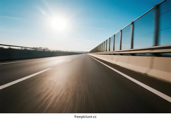 Blurred highway with bright sun shining in clear blue sky