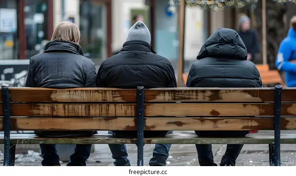 Three People Sitting on a Bench in the City