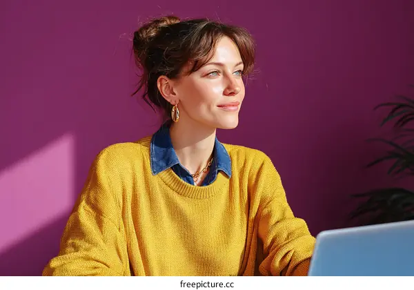 Young woman wearing yellow sweater working at desk with laptop