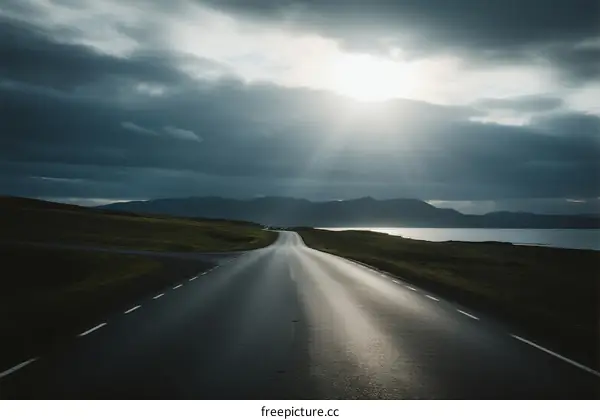 Long road under cloudy sky with sun rays shining through