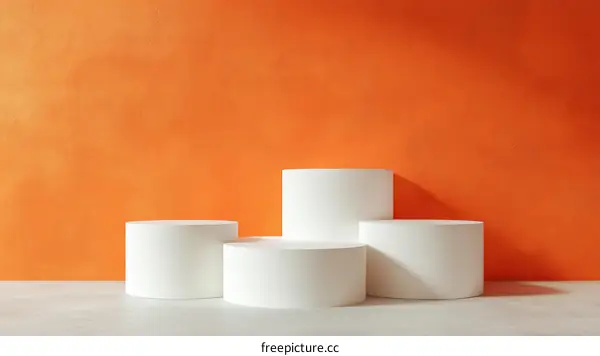 White Cylindrical Podiums Against an Orange Wall