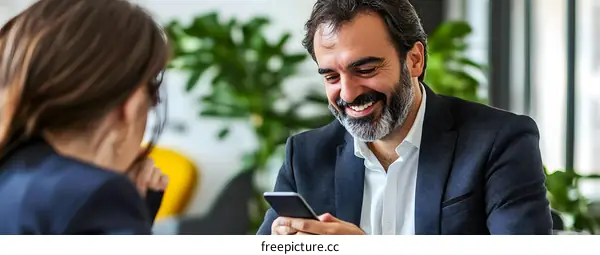 Happy Businessman Using Smartphone in Meeting