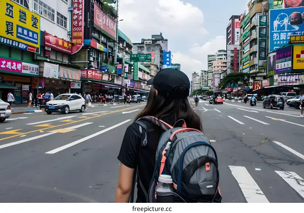 Young Woman Walking on Busy City Street With Backpack