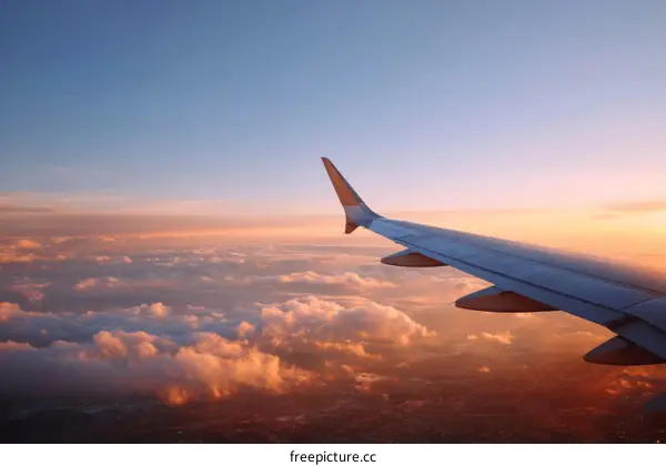 Aerial View of Airplane Wing at Sunset over Clouds