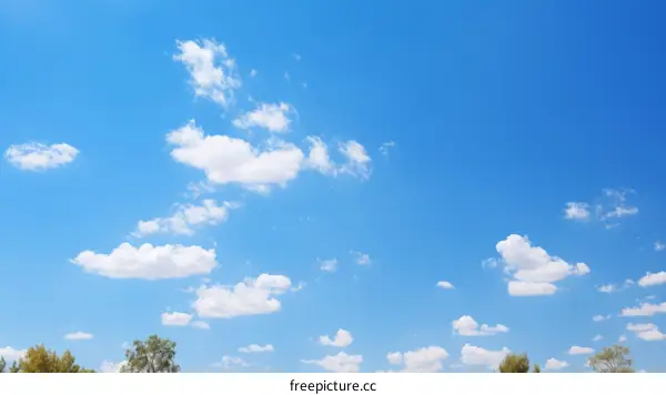 Blue sky and white clouds with green trees in the distance