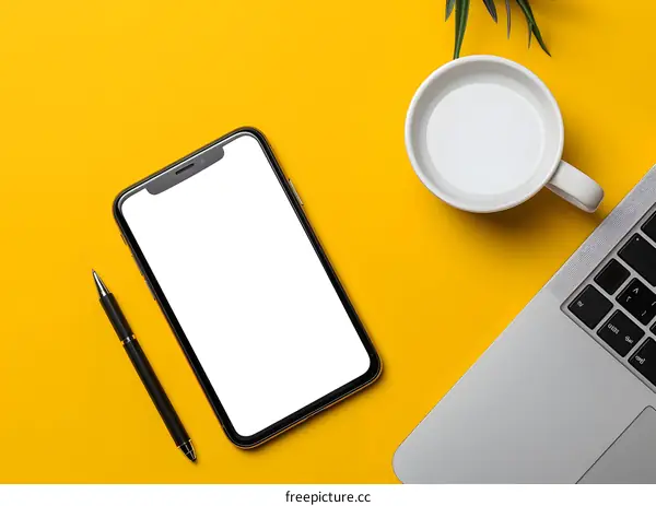Yellow Desk with Mobile Phone, Laptop, and Pen