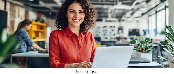 Smiling Woman Working on Laptop in Modern Office