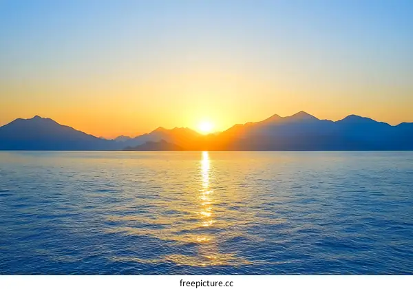 Silhouettes of Mountains at Sunset Over Water