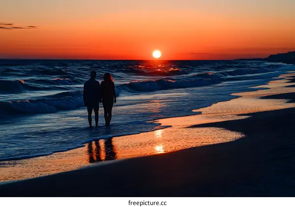 Silhouettes of Couple Walking on Beach at Sunset