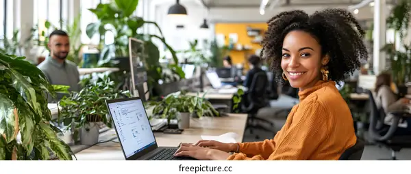 Smiling Black Woman Working on Laptop in Modern Office