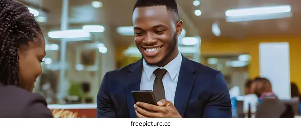 African American Businessman Uses Smartphone in Office