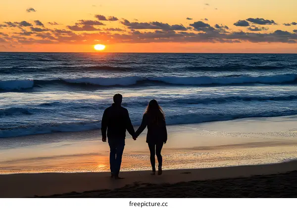 Silhouettes of Couple Holding Hands at Sunset on Beach