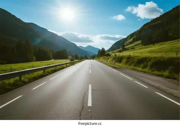 A scenic road through lush green mountains under a bright sun