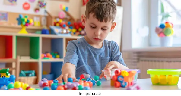 Toddler playing with colorful plastic beads at a table in a classroom