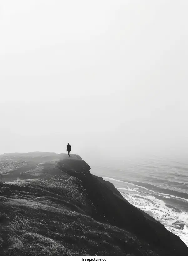 Man standing alone on a cliff overlooking the ocean