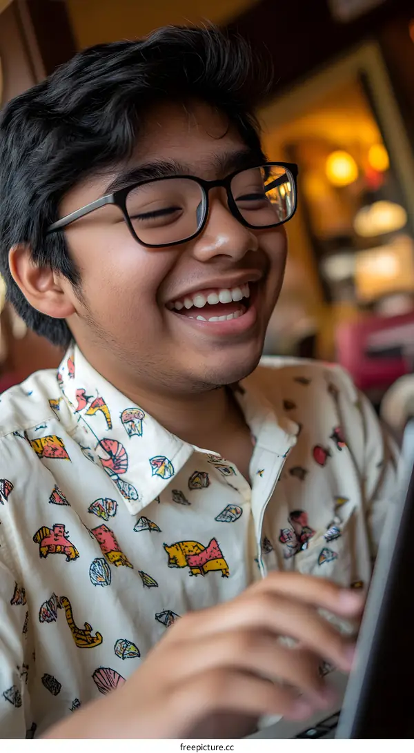 Happy Young Man in Glasses Smiling at Laptop