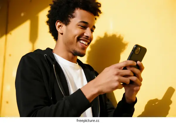 A man smiling while looking at his smartphone