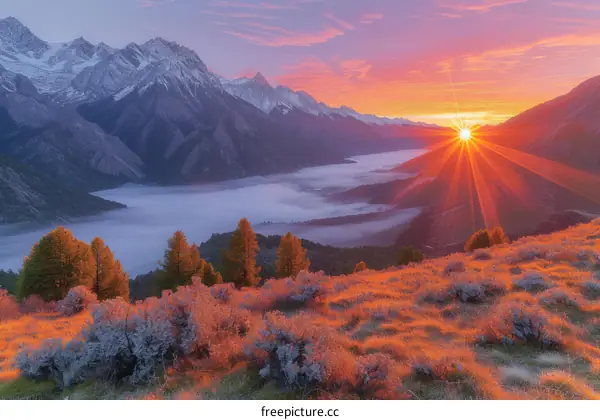 The setting sun casts a golden glow on the mountain peaks and the valley below