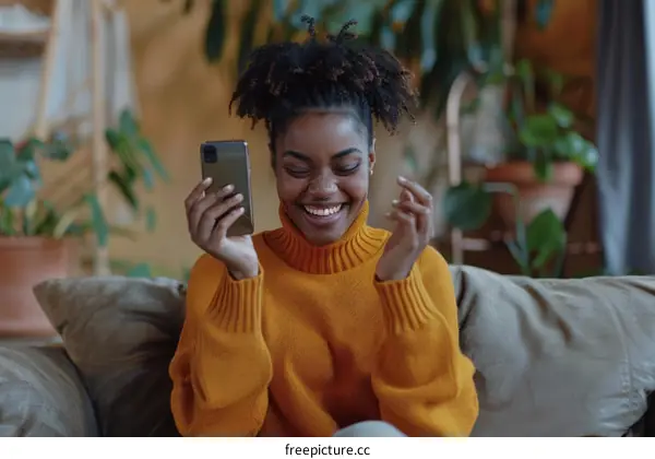 Laughing African American woman using smartphone at home