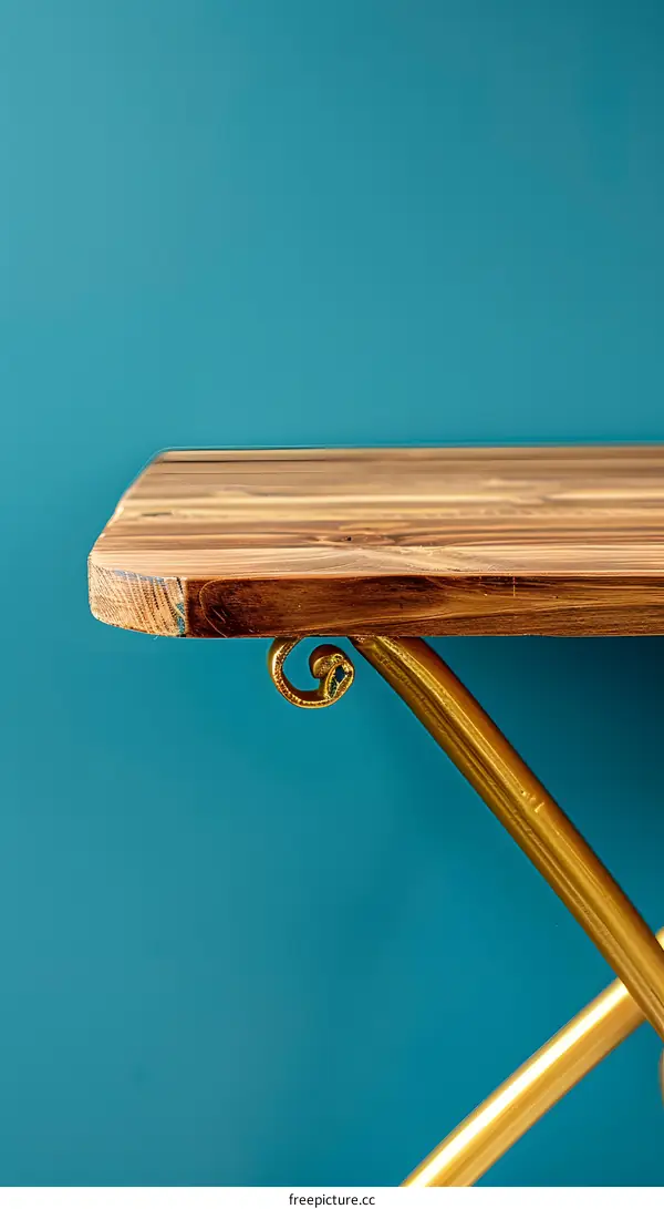 Wooden Tabletop with Gold Metal Legs Against Turquoise Wall