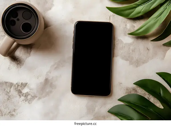 Smartphone With Green Leaves and a Coffee Cup on Beige Background