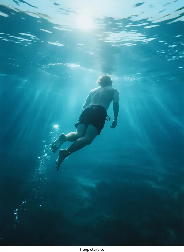 A Man Swimming Underwater with Sunlight Rays