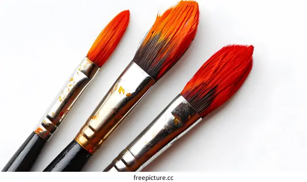 Three paintbrushes with red orange yellow paint