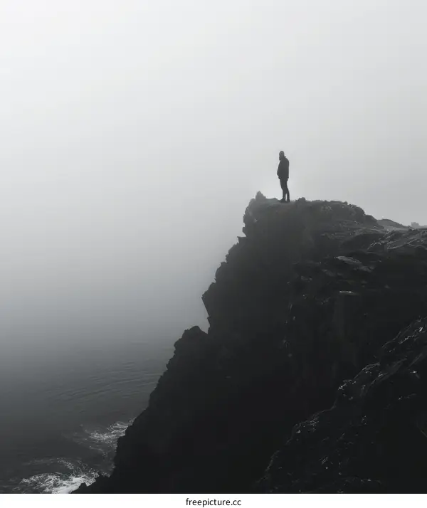 Man standing on a cliff overlooking a foggy sea
