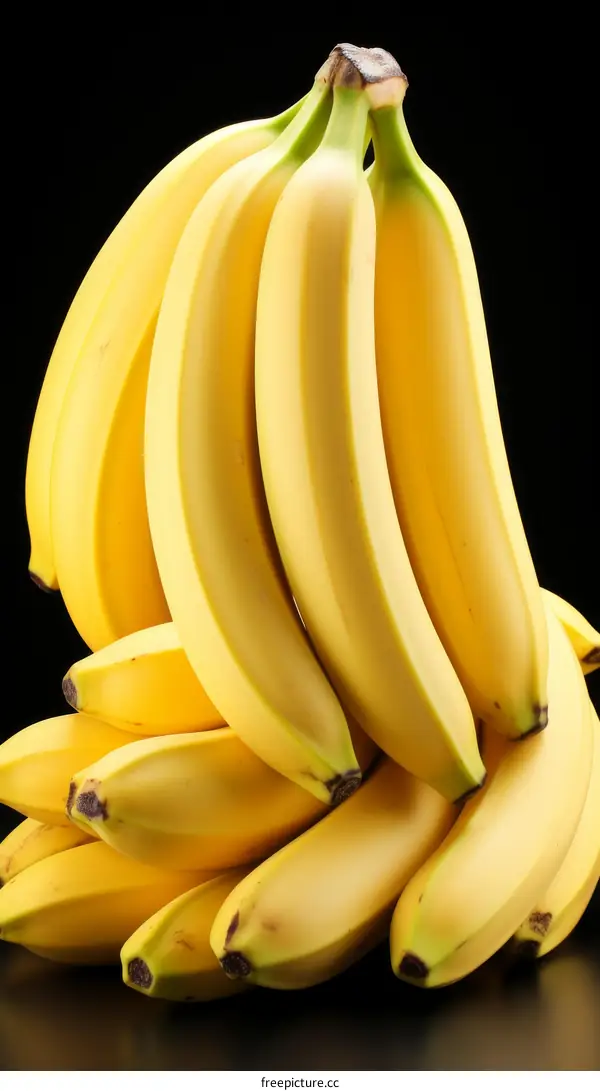 A bunch of ripe yellow bananas against a black background