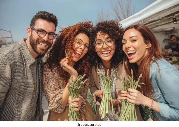 Happy friends enjoying fresh asparagus at a market
