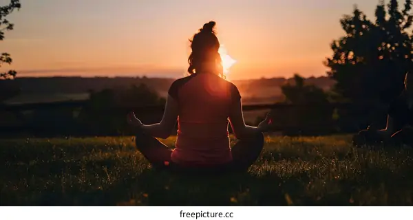 Woman Meditating in Field at Sunset
