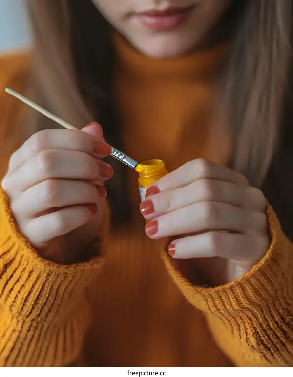 Woman Dipping a Paintbrush into a Jar of Yellow Paint