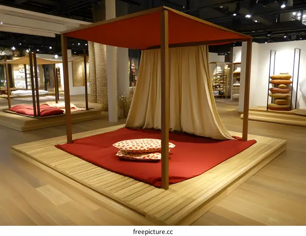 Wooden Canopy Bed with Red Pillows and Cream Curtains in a Modern Store