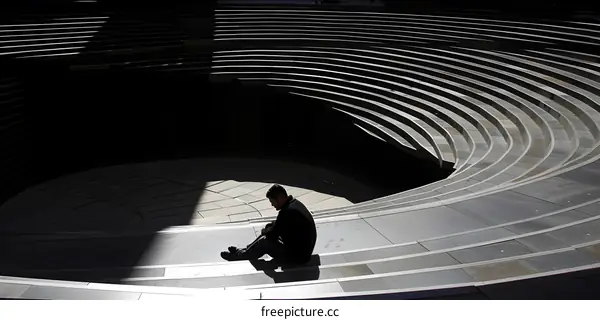 Man Sitting on Concrete Steps of Amphitheater