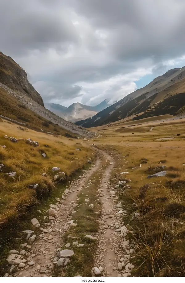 Mountain Path Through Valley With Cloudy Sky