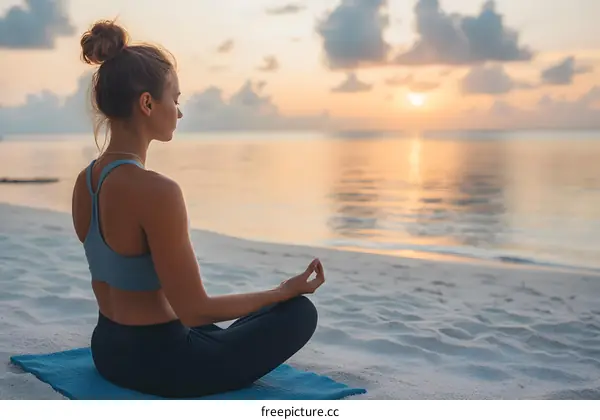 Woman practicing yoga on the beach at sunset
