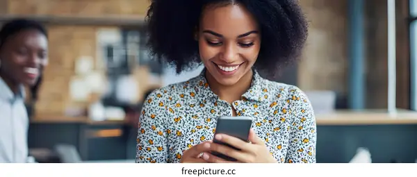 Smiling Black Woman Using Phone in Office