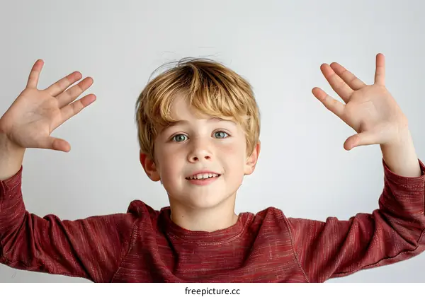 Portrait of a happy young boy with red hair and green eyes, raising his hands in the air