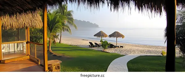 Tropical Beach View From A Hut With Palm Trees And Two Umbrellas