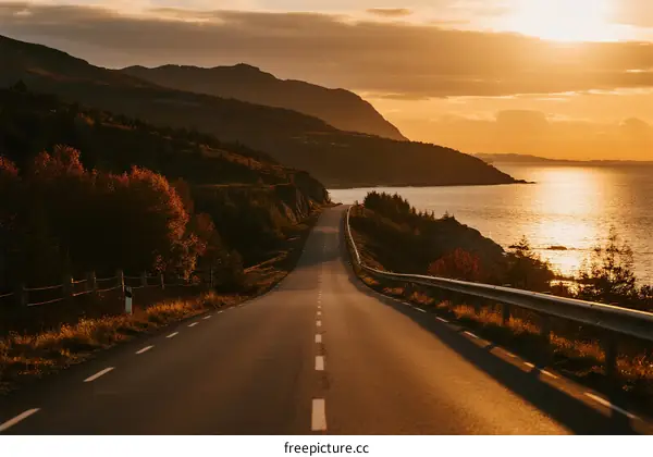 Sunset over a scenic coastal road with mountains and sea