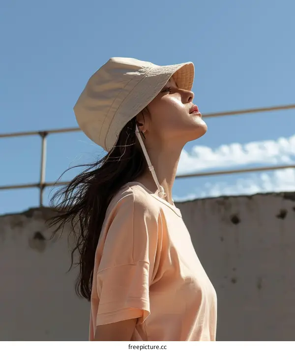 Young woman wearing a beige fisherman's hat looking up at the sky